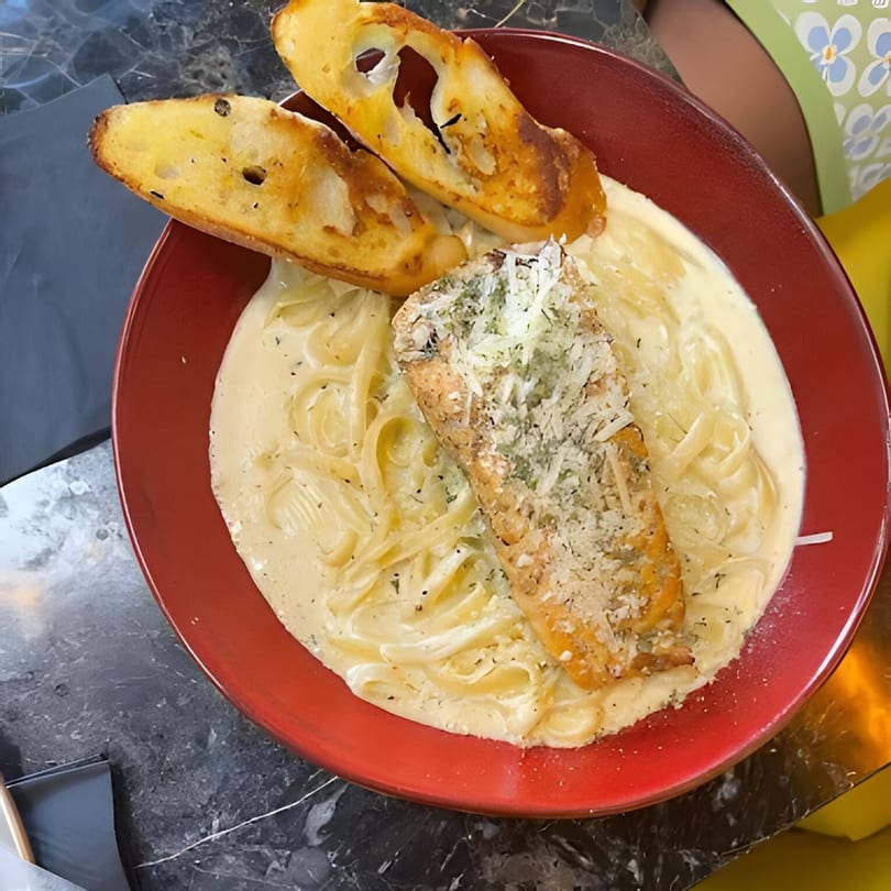 Al Dente Pasta & Pizza's creamy fettuccine Alfredo with grilled salmon and two slices of garlic bread.