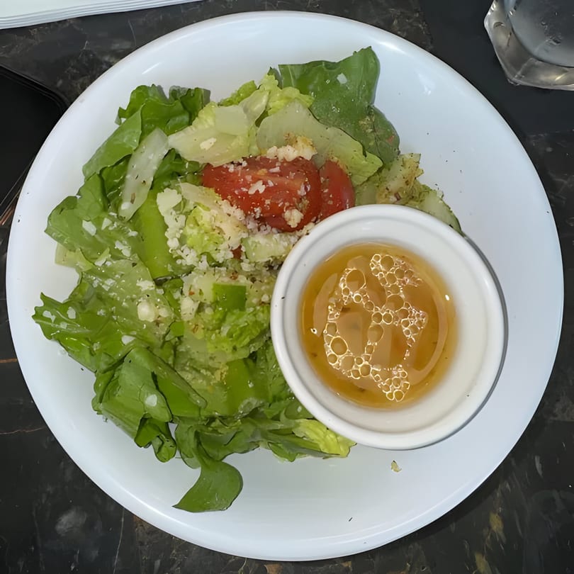 A fresh Italian side salad with lettuce, tomatoes, parmesan, and a vinaigrette dressing.
